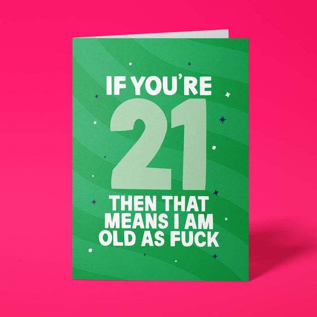 Green rude 21st birthday card standing upright on a bright pink background. White and pale mint chunky typography reads ‘IF YOU’RE 21 THEN THAT MEANS I AM OLD AS FUCK’ over green wave stripes with navy and white sparkle details.