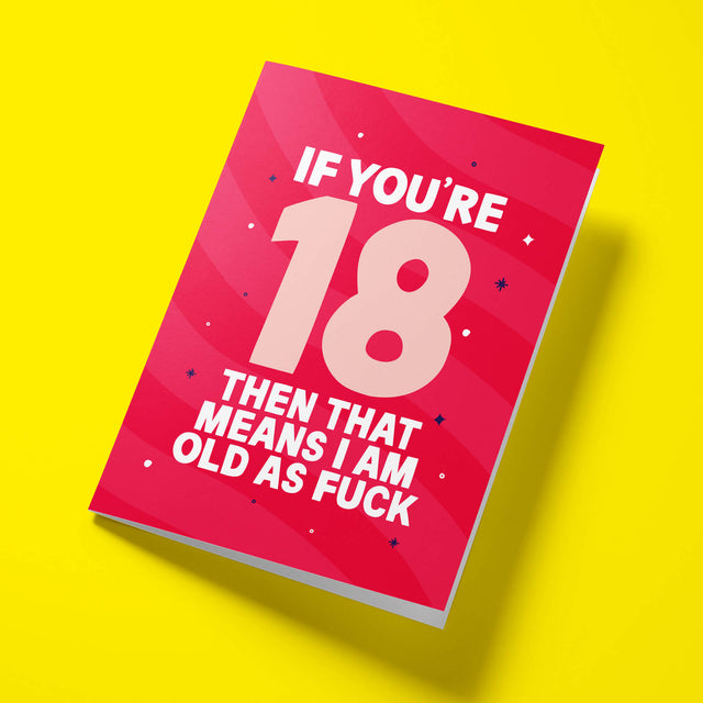 Raspberry pink ‘Old As Fuck’ 18th birthday card laid flat at an angle on a bright yellow background, with an oversized pale pink ‘18’ between white text.