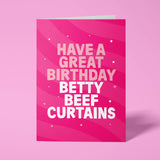 Hot pink rude birthday card standing upright against a pale pink background. Pale pink and white chunky typography reads 'HAVE A GREAT BIRTHDAY BETTY BEEF CURTAINS' over flowing pink wave stripes with white sparkle and dot details.