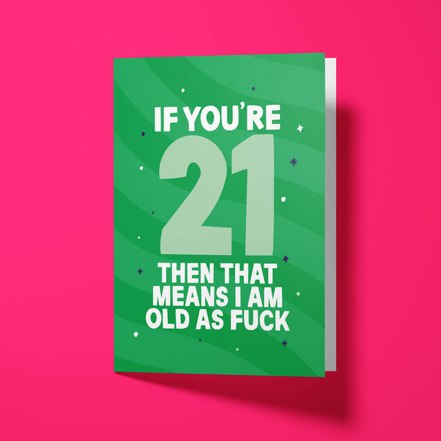 Green sweary 21st birthday card standing upright and slightly open on a bright pink background, showing the big ‘21’ and ‘OLD AS FUCK’