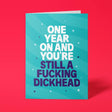 Teal rude birthday card with 'One year on and you're still a fucking dickhead' message in bold lettering