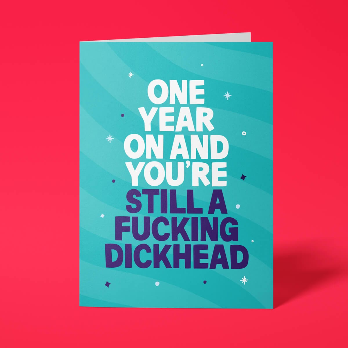 Teal rude birthday card with 'One year on and you're still a fucking dickhead' message in bold lettering