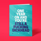 Teal rude birthday card with 'One year on and you're still a fucking dickhead' message in bold lettering